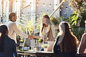 Bringing fresh business expertise to the team. colleagues shaking hands during a meeting at an outdoor cafe.