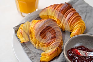 Brioche croissants on a plate with a small bowl of jam