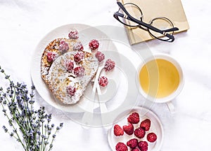 Brioche french toast with raspberry, powdered sugar and green tea. Cozy home still life, free time rest. On a light background, to