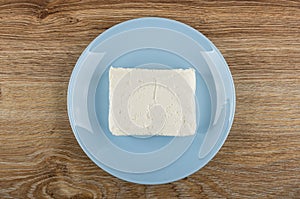 Briquette of cottage cheese in plate on wooden table. Top view