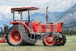 Farm tractor in a hay field against the Rocky Mountains