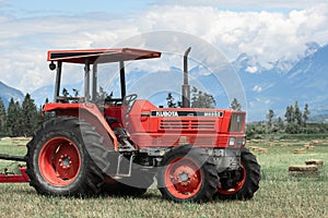 Farm tractor in a hay field against the Rocky Mountains