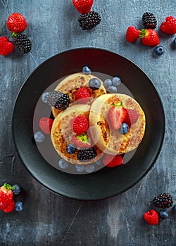 British Crumpets breakfast with blueberries, strawberries, blackberries, raspberries drizzled with icing sugar