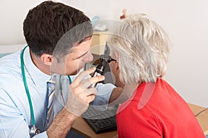 British doctor examining senior woman's ear