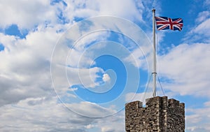 British flag rising over a castle tower