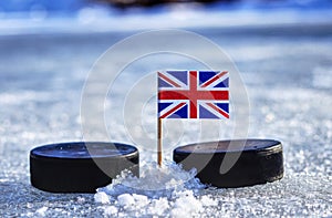 A british flag on toothpick between two hockey pucks on ice in winter classic. A Great Britain playing on World cup in group A.