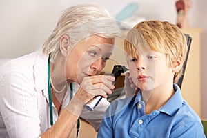 British GP examining young boy's ear