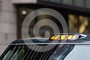 A british london black taxi cab sign with defocused  background