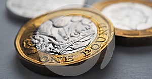 British money lies on gray surface. One pound sterling coin close-up. Economy and money. Bank of England. UK currency and