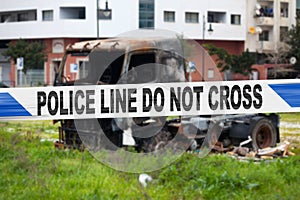 British police tape barricading a burnt truck