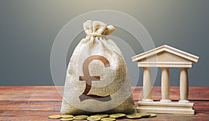 British pound sterling money bag and bank / government building. Tax collection and budgeting. Monetary policy. Support businesses