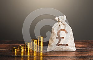 British pound sterling money bag and increasing stacks of coins. Rise in profits, budget fees. Investments. Raise incomes,