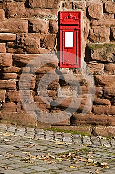 British red mail box mounted into stone wall.