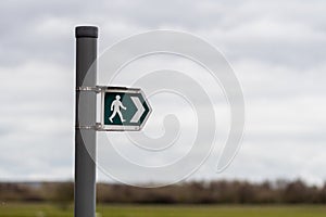 A British sign showing the direction of a public footpath
