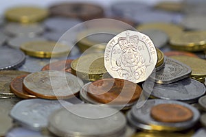 British twenty pence coin on top of a large pile of coins