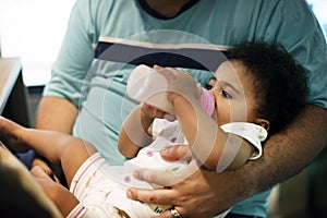 Brizilian father feeding toddler daughter
