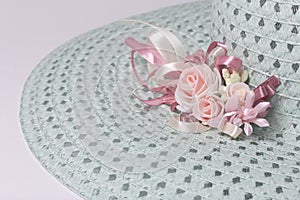 A broad-brimmed female hat is light green, with a buttonhole. Artificial flowers in the form of roses.