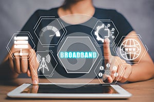 Person using digital tablet on desk with boardband icon on virtual screen