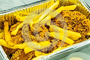 broasted chicken in a aluminum container with mayonnaise, hummus and french fries, on a white back ground.
