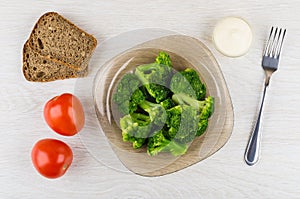 Broccoli in brown plate, bread, tomatoes, mayonnaise and fork