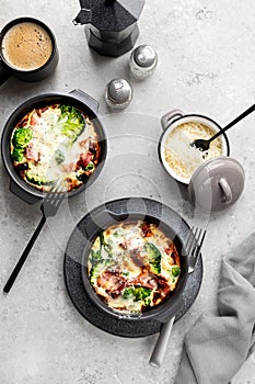 Broccoli casserole in a grey ceramic baking dish on a concrete background.