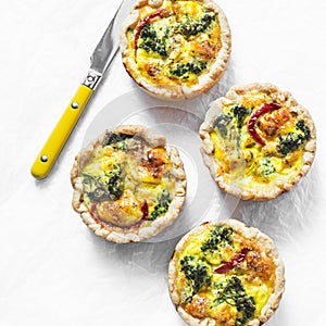 Broccoli, chicken, cheddar portioned pies on light background