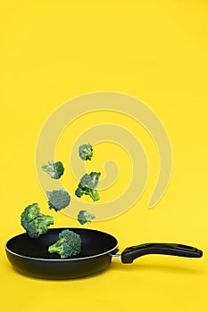 Broccoli in a pan on yellow background. Healthy concept. Copy space.