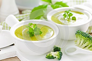 Broccoli soup in bowls on wooden kitchen table closeup. Healthy vegetarian dish. Diet food