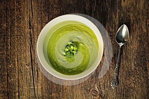 Broccoli soup with spoon on a wooden background