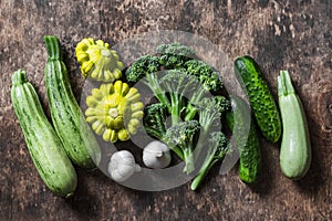 Broccoli, zucchini, squash, garlic, cucumbers - fresh organic vegetables on a wooden background, top view. Flat lay