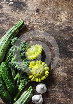 Broccoli, zucchini, squash, garlic, cucumbers - fresh organic vegetables on a wooden background, top view. Flat lay
