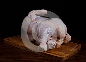 The broiler chicken lies on a wooden cutting board