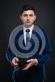 Broke businessman with empty wallet on dark background