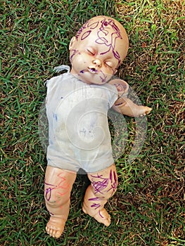 Broken and abandoned doll in the grass.