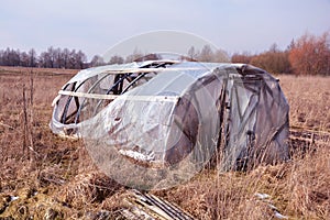 Broken abandoned plastic greenhouse in early spring