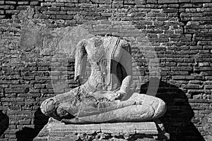 Broken ancient Buddha statue  with bricks background