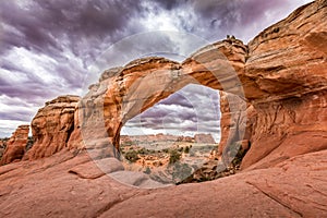 Broken Arch in the Arches National Park, Utah and dramatic dark clouds