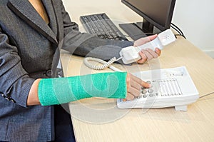 Broken arm bone in cast and holding telephone