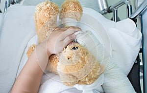 Broken arm in cast holding a teddy bear