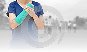 Broken arm with green cast on blurred background kid soccer play