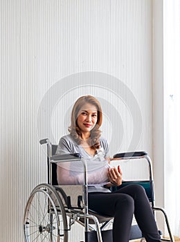 Broken arm woman with arm sling sponsored in her hands sitting on a wheelchair Ideas for accident Injuries and health care