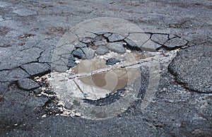 Broken asphalt. Puddle on cracked road