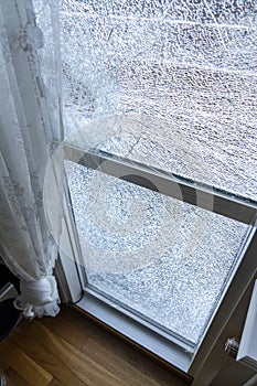 Broken balcony glass door window with shattered glass