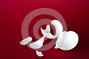 Broken ball decoration of a Christmas tree. White shards on a red background. Copy space