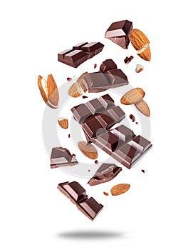 Broken bar of dark chocolate with almonds in the air isolated on a white background