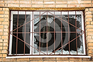 Broken barred window in an abandoned brick house.Hooliganism, vandalism