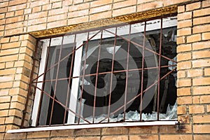 Broken barred window in an abandoned brick house.Hooliganism, vandalism