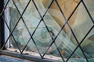 Broken barred window in an abandoned brick house.Hooliganism, vandalism