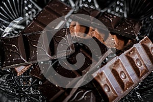 broken bars of different chocolate stacked on a light background