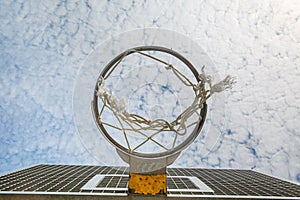 A broken basketball net dangles from a hoop attached to a metal backboard.